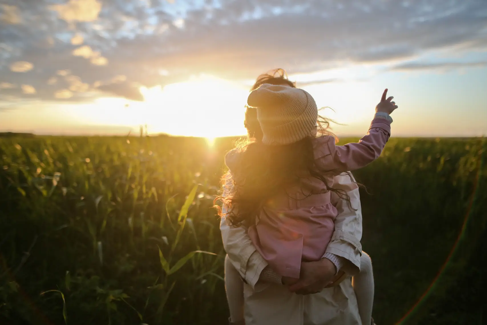 A child walking through a field at sunset